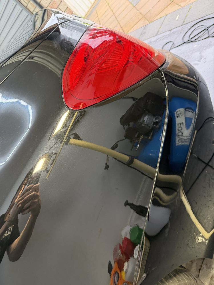 The same black panel after paint correction, with a clear mirror reflection