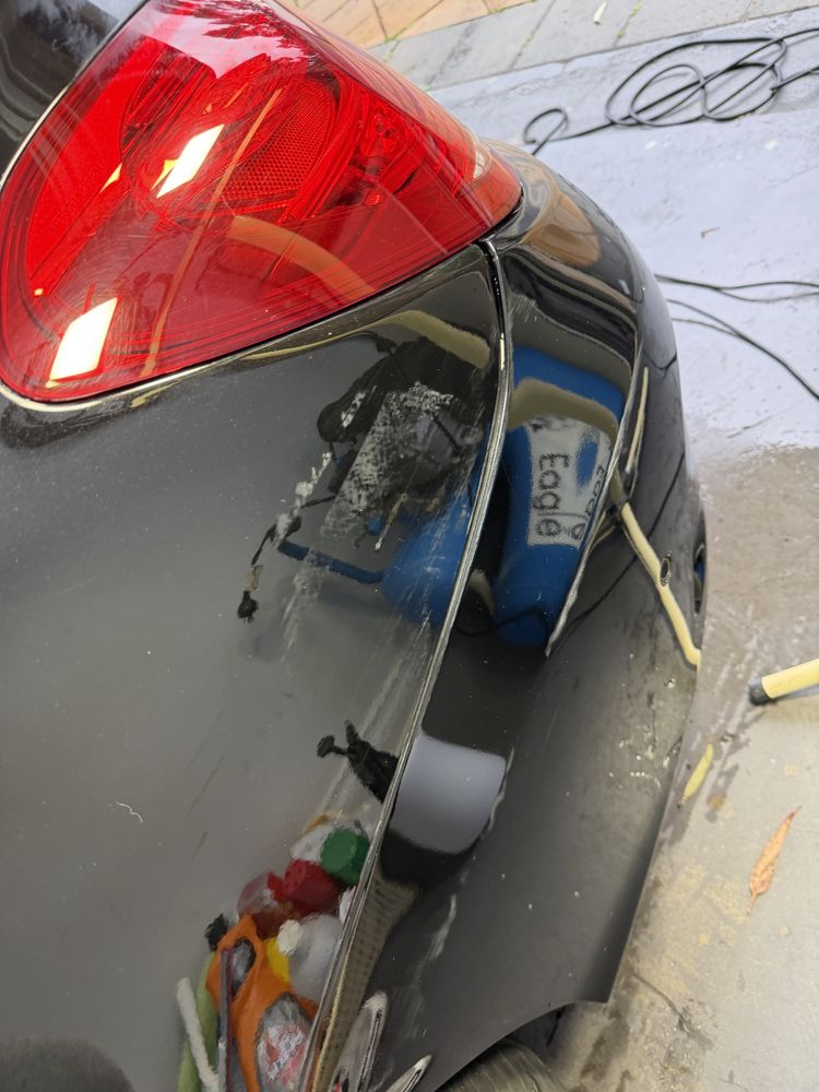 Black rear quarter panel covered in swirl marks before paint correction