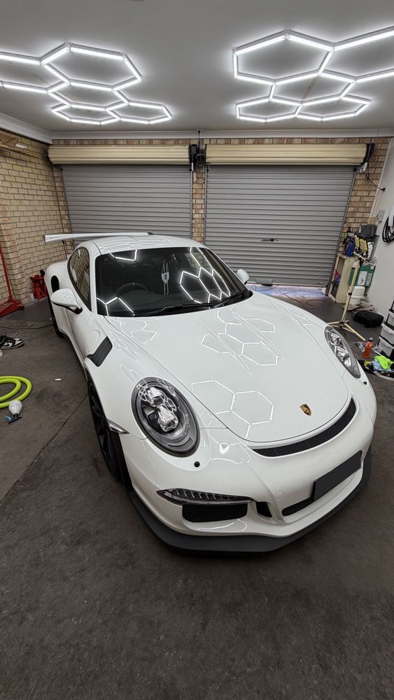White Porsche 911 GT3 RS finished in the Crown Detailing workshop under hexagon lights