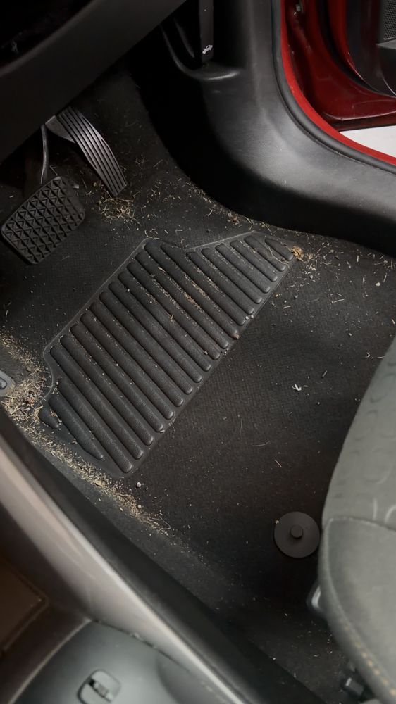 Driver footwell covered in dirt and debris before an interior detail